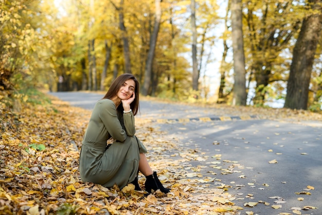 Retrato de mujer morena en otoño parque con vestido verde oliva