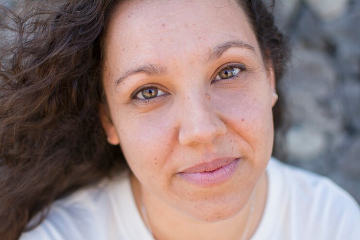 Retrato de una mujer morena con el pelo rizado y con hermosos y penetrantes ojos verdes.