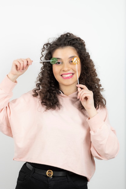 Retrato de mujer morena rizada con piruletas de colores posando.