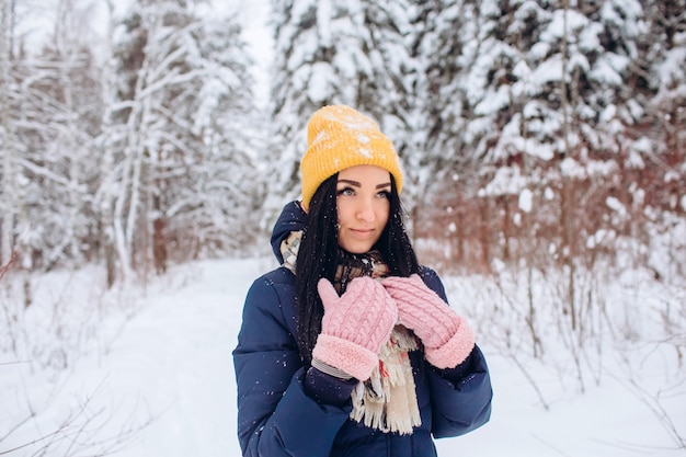 Retrato de una mujer morena con un sombrero amarillo sobre un fondo de un bosque de invierno