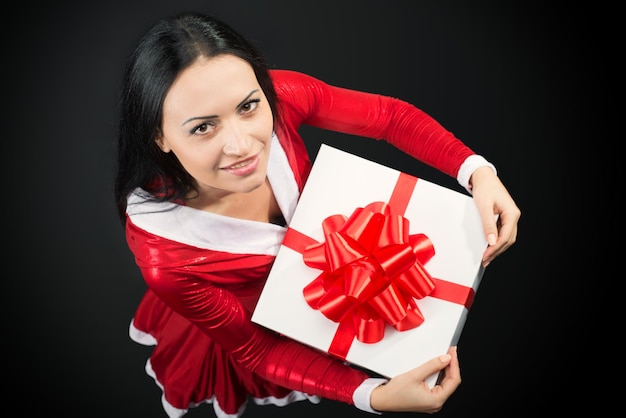 Retrato de una mujer morena sonriente con regalo de Navidad