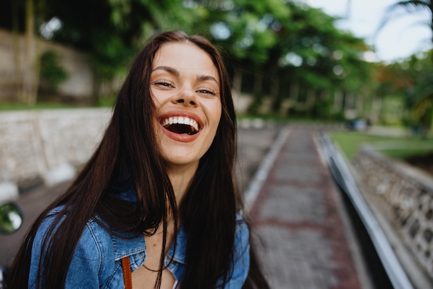 Retrato de una mujer morena sonrisa con dientes caminando afuera contra un telón de fondo de palmeras en los trópicos vacaciones de verano y recreación al aire libre el estilo de vida despreocupado de un estudiante independiente