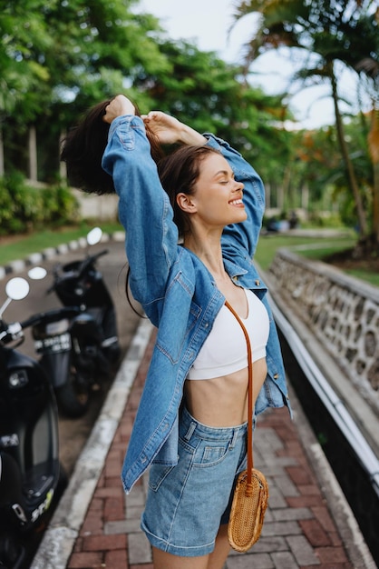 Foto retrato de una mujer morena sonrisa con dientes caminando afuera contra un telón de fondo de palmeras en los trópicos vacaciones de verano y recreación al aire libre el estilo de vida despreocupado de un estudiante independiente