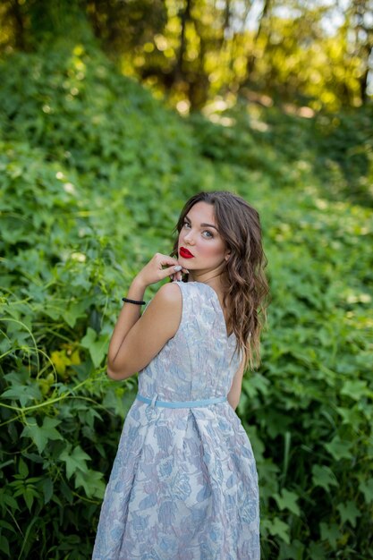 Retrato de una mujer morena con un vestido de verano y lápiz labial rojo en plantas verdes