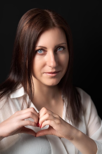 Retrato de mujer mostrando signo de forma de corazón con ambas manos y mirando a la cámara