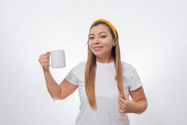 Retrato de mujer mostrando una taza blanca Persona sosteniendo una taza de café fondo blanco.