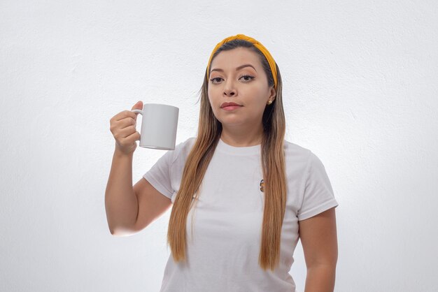 Retrato de mujer mostrando una taza blanca Persona sosteniendo una taza de café fondo blanco.