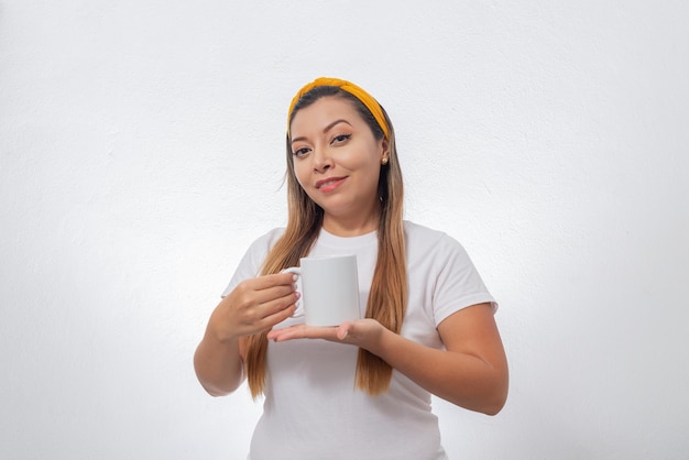 Retrato de mujer mostrando una taza blanca Persona sosteniendo una taza de café fondo blanco.