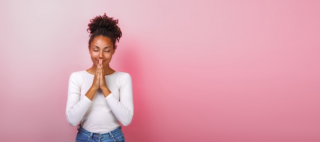 Retrato de mujer mulata en actitud de súplica con sonrisa y ojos cerrados sobre rosa