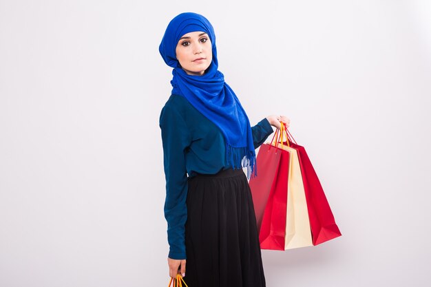 Retrato de mujer musulmana asiática con bolsas de compras sobre fondo blanco.