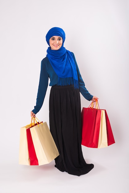 Retrato de mujer musulmana asiática con bolsas de compras sobre fondo blanco.