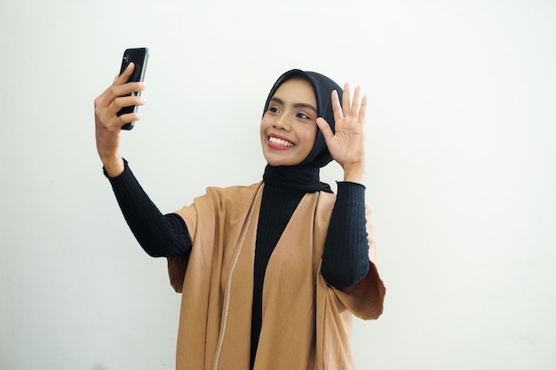 Retrato de una mujer musulmana asiática feliz usando hijab tomando selfie con teléfono