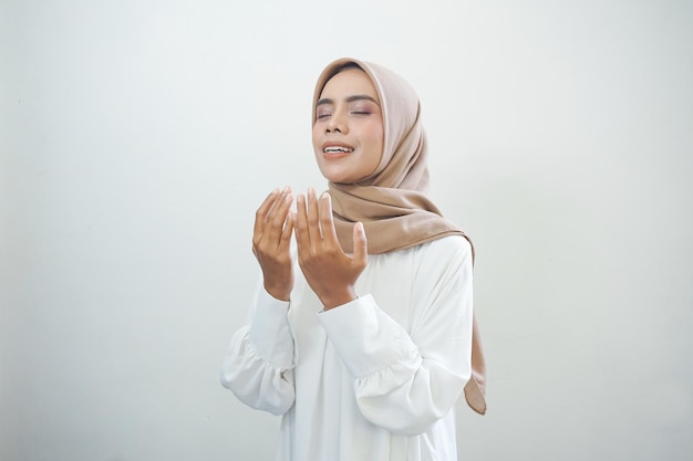 Retrato de mujer musulmana asiática orando con el brazo abierto aislado sobre fondo blanco.