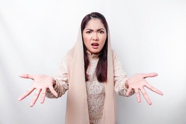 Un retrato de una mujer musulmana asiática que lleva un pañuelo en la cabeza aislado por un fondo blanco parece deprimido