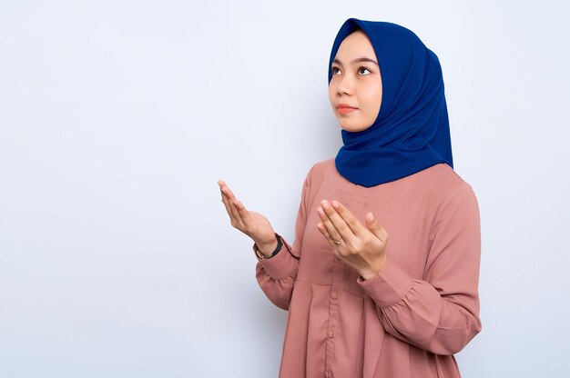 Retrato de mujer musulmana asiática rezando con el brazo abierto aislado sobre fondo blanco Concepto de estilo de vida religioso de la gente