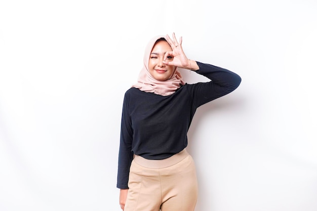 Retrato de una mujer musulmana asiática sonriente dando un gesto de mano OK aislado sobre fondo blanco.