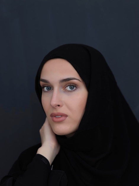 Retrato de mujer musulmana joven moderna en abaya negra. Niña árabe con ropa tradicional y posando frente a una pizarra negra. Representando el estilo de vida árabe moderno y rico
