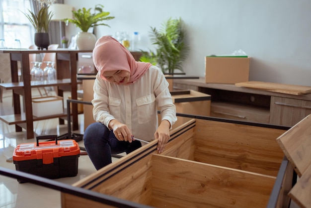 Foto retrato de mujer musulmana montando muebles nuevos en casa