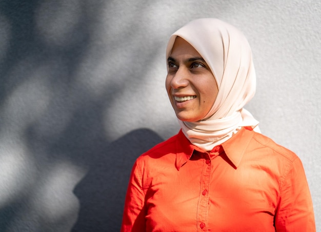 Retrato de mujer musulmana sonriente contra la pared