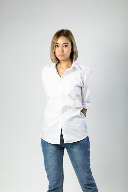 Retrato de mujer de negocios alegre bastante linda asiática joven manteniendo los brazos cruzados y sonriendo de cerca y mirando a cámara sobre fondo blanco. maquillaje natural y dientes blancos