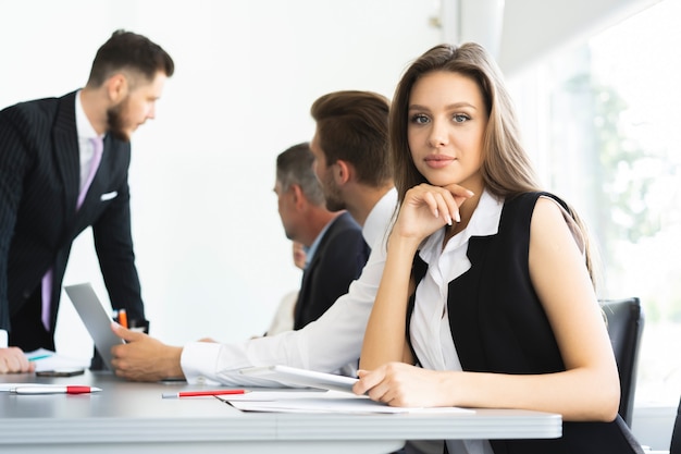 Retrato de una mujer de negocios alegre sentado a la mesa en la oficina y mirando a la cámara.