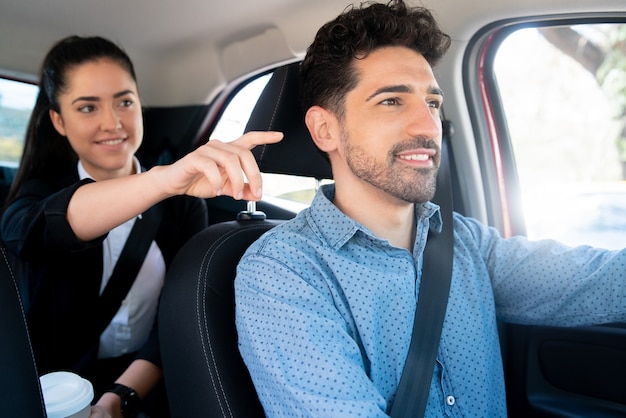 Retrato de mujer de negocios apuntando algo a su taxista