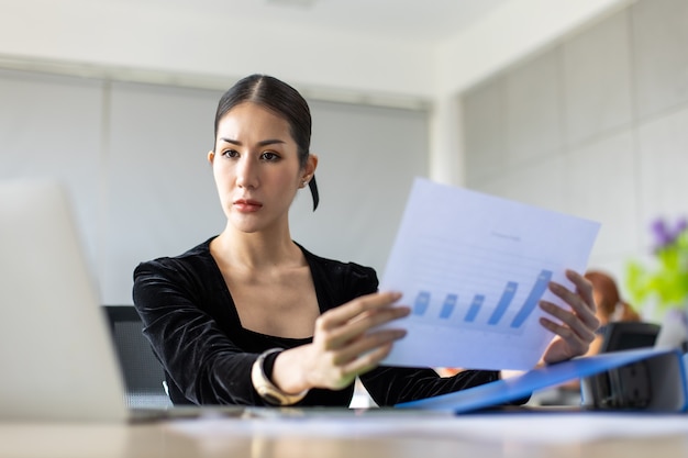 Retrato de mujer de negocios asiática joven ocupada trabajando en equipo portátil en la oficina en casa moderna.