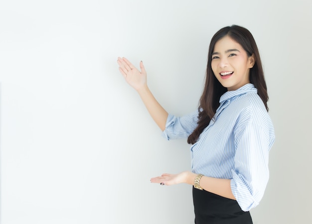 Retrato de la mujer de negocios asiática joven que señala para arriba sobre el fondo blanco.