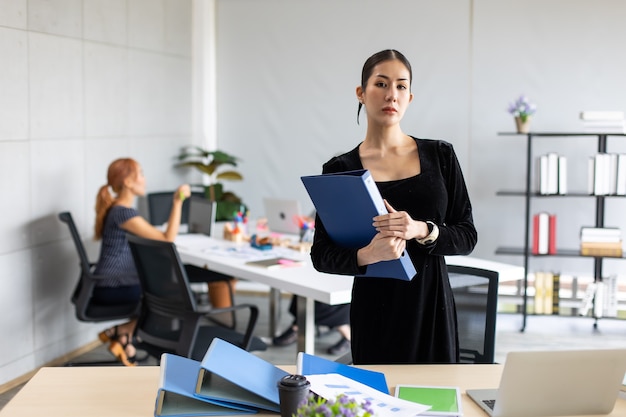 Retrato de mujer de negocios asiática de pie y mirando a la cámara en la oficina en casa moderna.