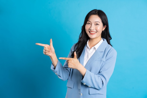 Retrato de mujer de negocios asiática posando sobre fondo azul.