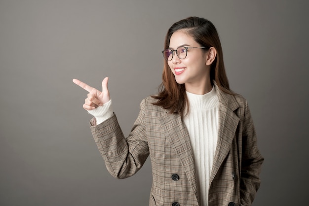 Retrato de la mujer de negocios atractiva en fondo del gris del estudio