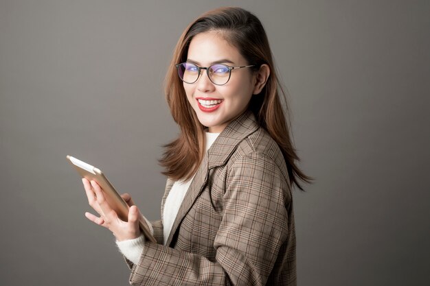 Retrato de la mujer de negocios atractiva en fondo del gris del estudio