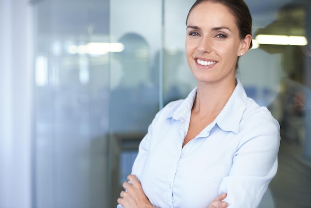 Foto retrato de una mujer de negocios con los brazos cruzados, confianza y carrera en el espacio de la oficina de contabilidad, asesor financiero, contable profesional o gerente de proyecto financiero en una maqueta con una sonrisa en la cara.