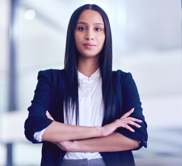 Retrato de mujer de negocios y brazos cruzados con la gestión y motivación de la visión de la empresa Éxito joven empleada y abogada profesional en un bufete de abogados en la oficina con orgullo y confianza en el trabajo