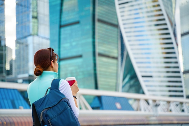 Retrato de mujer de negocios caminando y sonriendo al aire libre y una taza de café