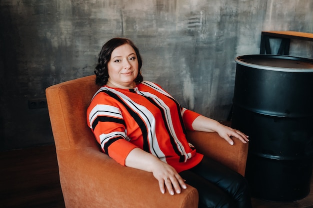 Retrato de una mujer de negocios en una chaqueta de rayas sentada en un sofá en el interior