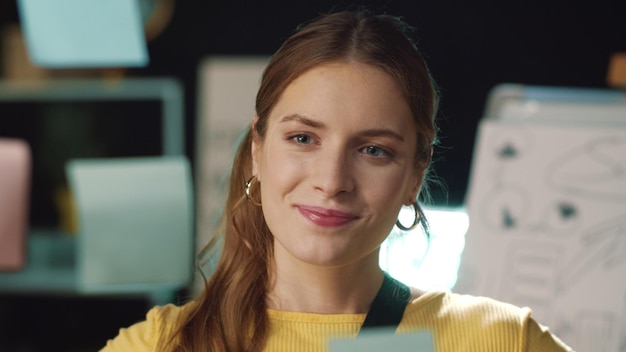 Retrato de una mujer de negocios disfrutando del resultado del proyecto en una oficina moderna Chica hipster alegre sacando una pegatina de un tablero de vidrio en el interior Una profesional satisfecha que encuentra una buena respuesta en el coworking