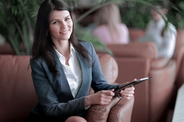 Retrato de una mujer de negocios ejecutiva con un portapapeles en el fondo del centro de negocios