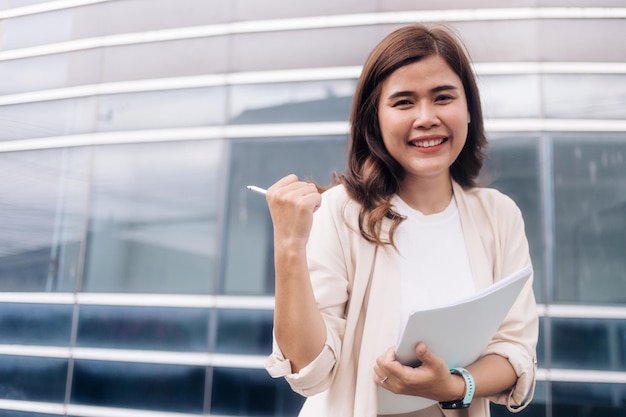 Retrato de una mujer de negocios feliz sosteniendo un documento y una pluma en la ciudad