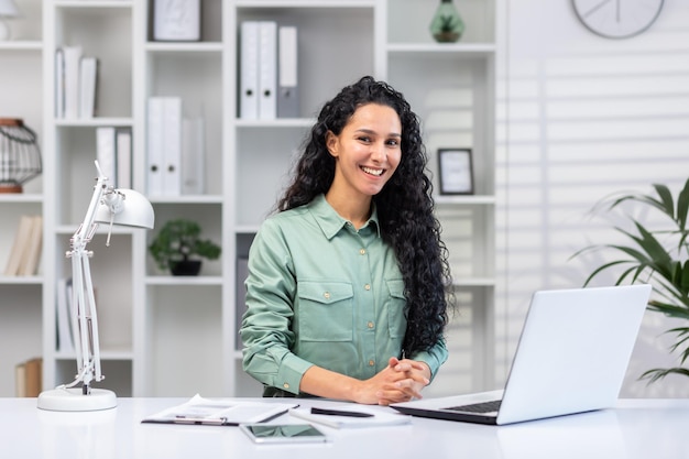 Retrato de mujer de negocios hermosa exitosa mujer hispana en la oficina en casa sonriendo y mirando