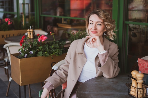 Retrato de mujer de negocios hermosa sentada en un café de la calle