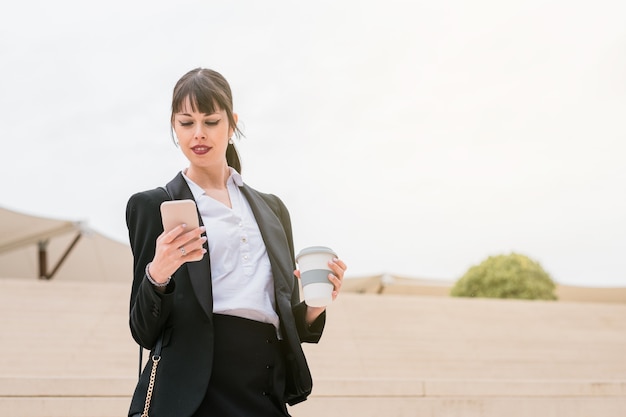 Retrato de mujer de negocios hermosa con smartphone en su camino al trabajo