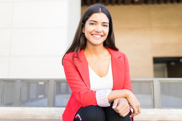 Retrato de una mujer de negocios inteligente y confiada sonriendo mientras se sienta fuera de la oficina