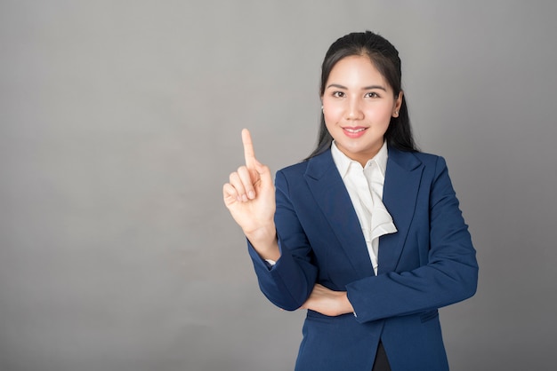 Retrato de mujer de negocios inteligente en traje azul apuntando con su dedo