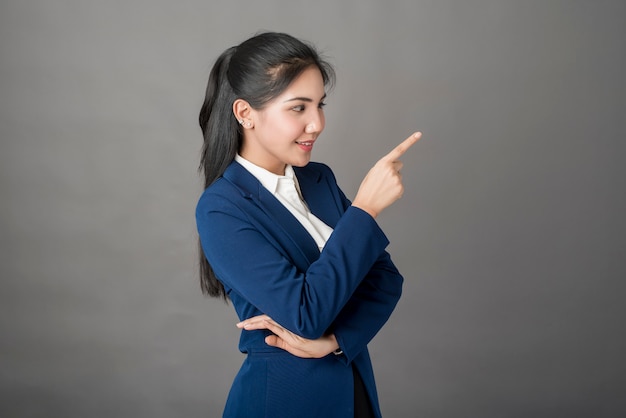 Retrato de mujer de negocios inteligente en traje azul sobre fondo gris, tiro del estudio