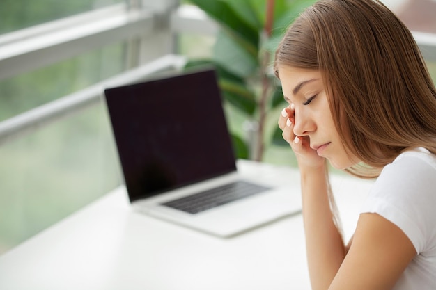 Retrato de mujer de negocios joven cansado con la computadora portátil