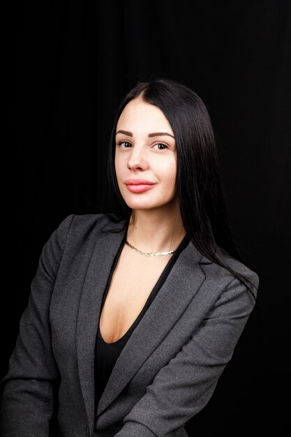 Retrato de mujer de negocios joven en una chaqueta gris sobre negro.