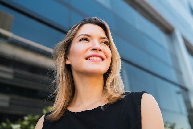 Retrato de mujer de negocios joven permanente fuera de edificios de oficinas. Concepto de negocio y éxito.