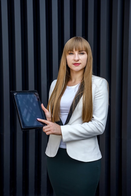 Retrato de mujer de negocios joven con tableta sobre fondo gris