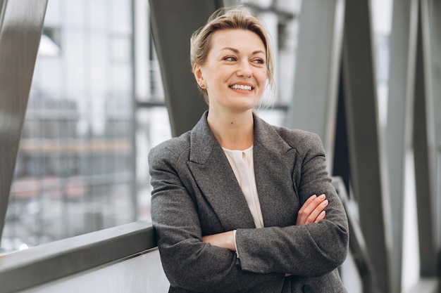 Retrato de una mujer de negocios madura sonriendo con emociones en la oficina moderna y el entorno urbano